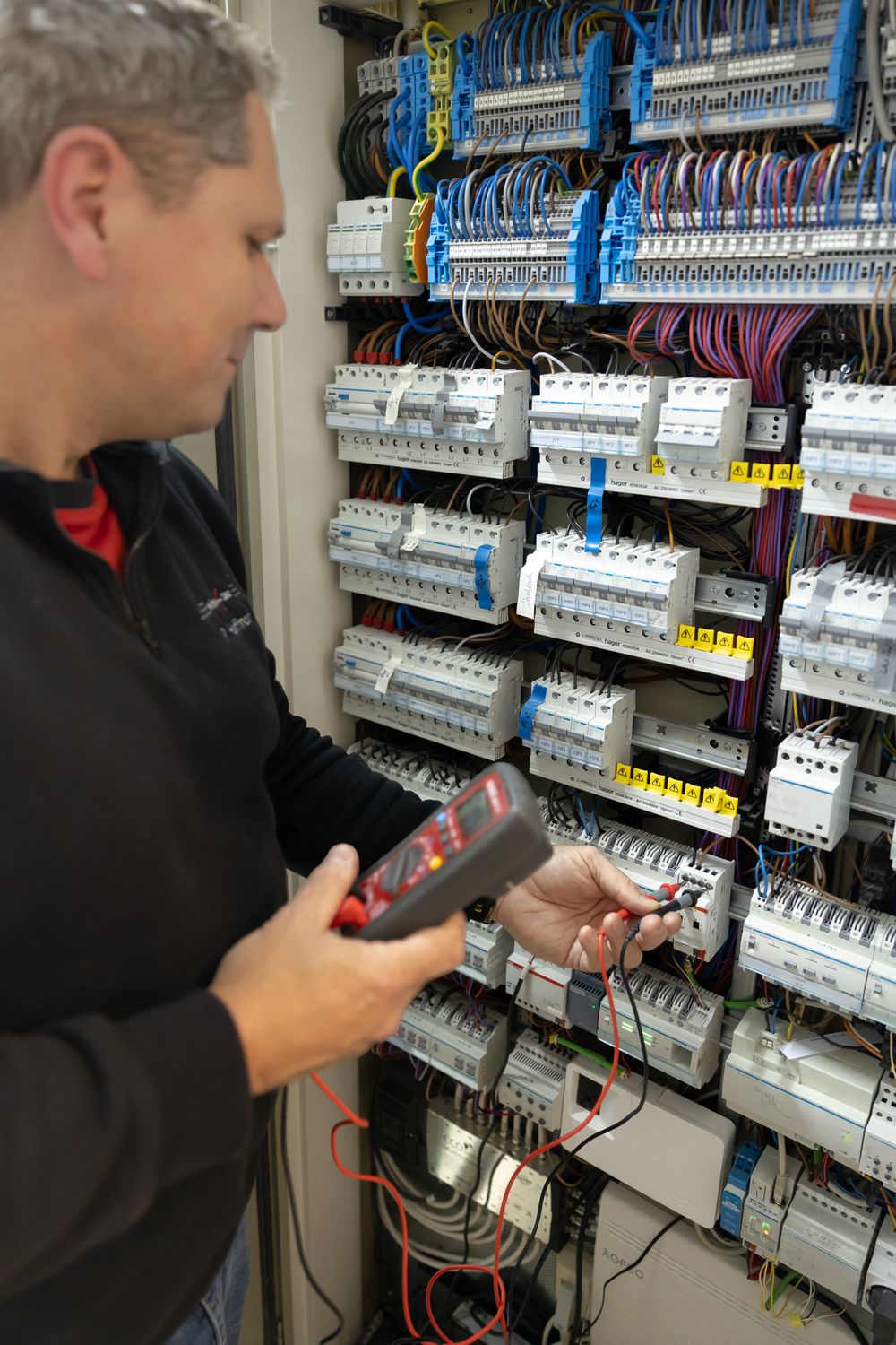 Elektromeister der elho-tec prüft mit einem Messgerät einen Sicherungs- und Verteilerkasten beim E-Check