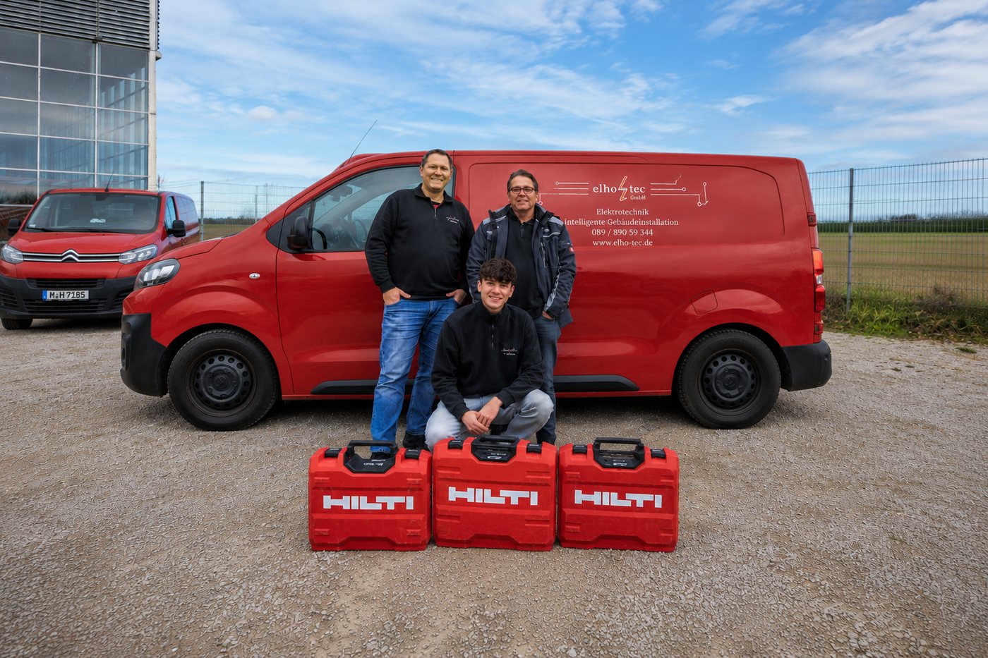 Das Team der elho-tec GmbH mit Werkzeugkoffern vor dem beschrifteten roten Servicefahrzeug